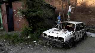 Дети играют на разбитом автомобиле в Мариуполе.