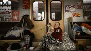 Женщина держит собаку в поезде на станции харьковского метро, используемой в качестве бомбоубежища.